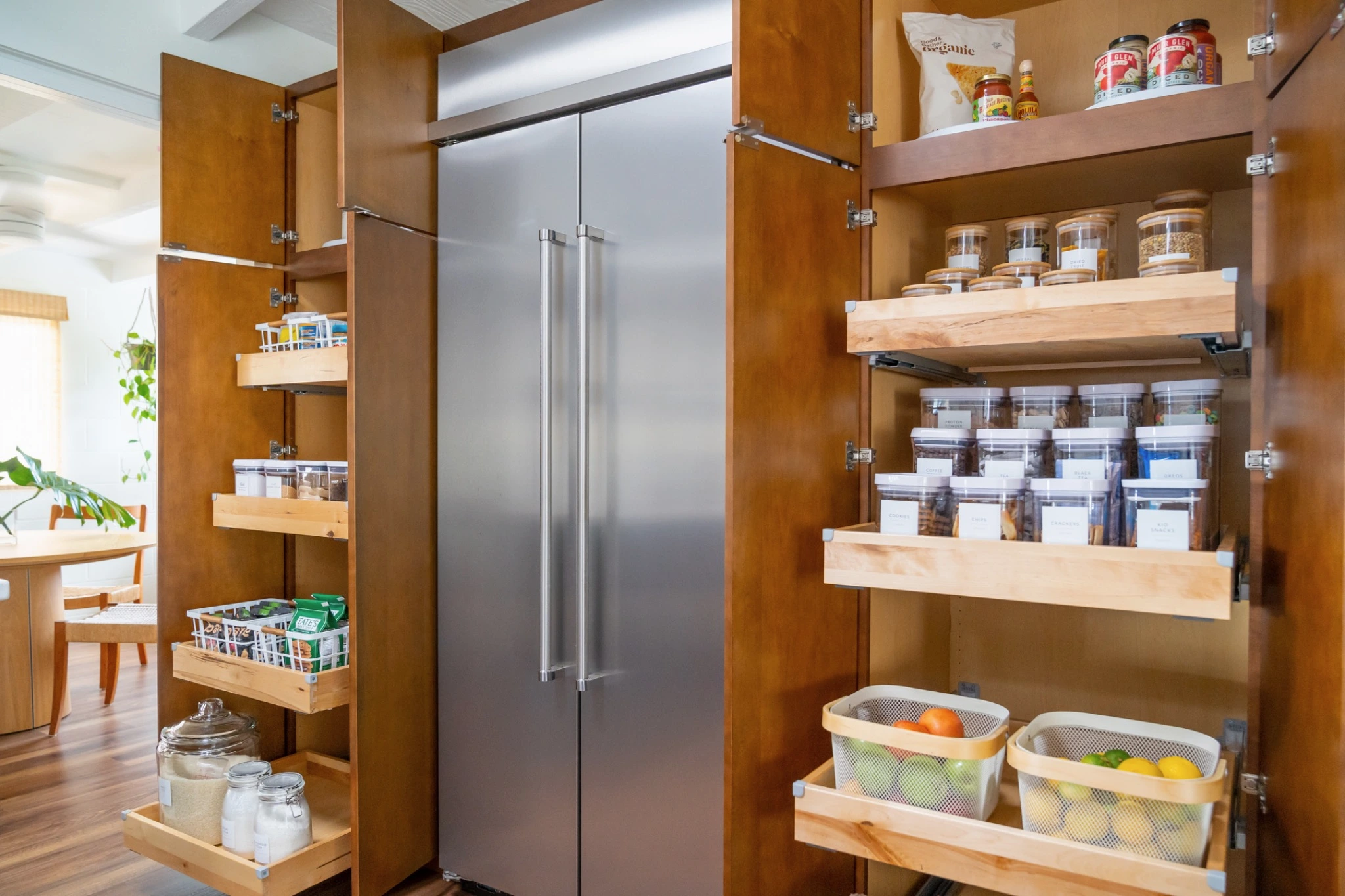 Open pantry cabinetry with tiered pull-out shelves and organized food storage around the refrigerator